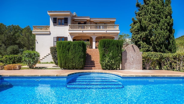 Ein zweistöckiges Haus mit Pool davor.