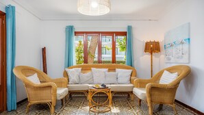 A room with a sofa, two wicker chairs, a patterned floor, a window with curtains, and a painting on the wall. - Vacation Home "Family Home Mhm" near Beach with Private Terrace & Wi-Fi (Cala lliteres)