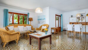 A living room with a sofa, chairs, a dining table, and a kitchen area with cabinets and a sink. - Vacation Home "Family Home Mhm" near Beach with Private Terrace & Wi-Fi (Cala lliteres)
