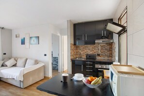 A modern kitchen with dark cabinets, a microwave, and a toaster. There is a dining table with a bowl of fruit and a cup.