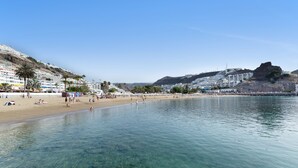 A beach with clear water, a sandy shore, and buildings in the background. - Vacation Home "Sunset" with Sea View, Shared Pool & Wi-Fi (Puerto Rico)