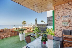 A patio with a view of the sea, outdoor furniture, and a brick wall with motivational signs.