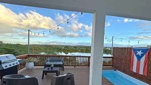 A covered outdoor area with a grill, seating, and a view of a lake. - Beach House with Pool in Playa Santa - Casa Perla (Guánica)