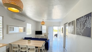 A modern kitchen with a dining area, a TV, and a view of the outside. - Beach House with Pool in Playa Santa - Casa Perla (Guánica)