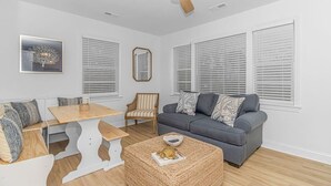 Una sala moderna con un sofá gris, una mesa de comedor de madera y un ventilador de techo.