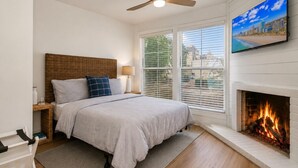 A bedroom with a bed, a fireplace, a television, and a window with blinds. - Myrtle Beach Haven . Walkable to Boardwalk, Beach & Dining. Pet Friendly! (Myrtle Beach)