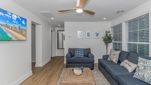 A modern living room with a grey sofa, a wooden coffee table, and a ceiling fan. - Myrtle Beach Haven . Walkable to Boardwalk, Beach & Dining. Pet Friendly! (Myrtle Beach)
