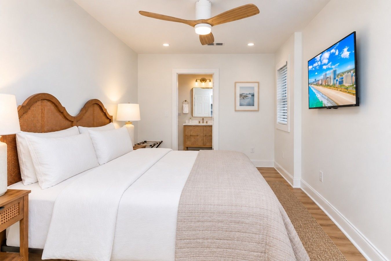 A hotel room with a bed, a ceiling fan, a television, and a bathroom visible through an open door.