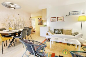 A modern living room with a dining area, featuring a sofa, coffee table, and chairs. - Tyredelle - Carnac - Gîte (CARNAC)