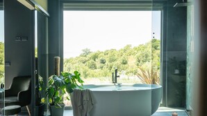 Un baño moderno con una bañera independiente, una silla y plantas en macetas.