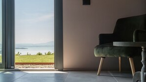 Una habitación con un amplio ventanal corredera que da a una vista panorámica de un lago y montañas.