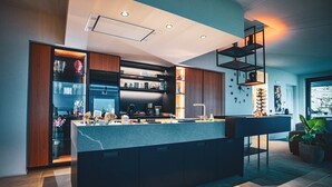 Una cocina moderna con una isla central, electrodomésticos integrados y un estante estilo entrepiso.