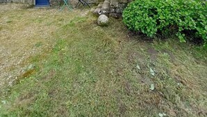 A stone building with a sloped roof, a blue door, and a small window. There are two blue chairs outside and a small garden area. - Ker Zen - Locmariaquer (LOCMARIAQUER)