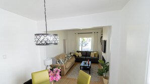 Una sala de estar moderna con una mesa de comedor, sillas, un sofá y una mesa de centro.