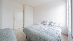 Un dormitorio con cama, mesita de noche y puerta.