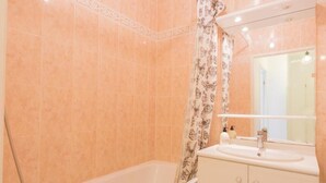 Un baño con bañera, lavamanos y espejo.