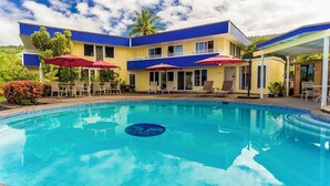 Ein Hotel mit Schwimmbad, Außenbereich und einer Fassade in Blau und Gelb.