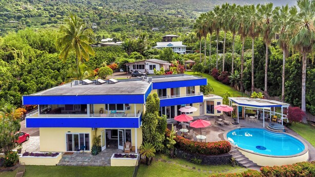 Ein modernes, zweistöckiges Gebäude mit Pool, umgeben von üppiger Vegetation und Palmen.