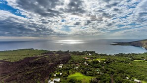 Eine Küstenlandschaft mit Blick auf das Meer, ein kleiner Ort mit Häusern und eine Straße, die zum Wasser führt.