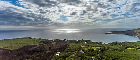 A coastal landscape with a view of the sea, a small settlement with houses, and a road leading to the water.