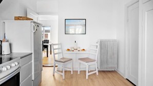 A compact kitchen with a refrigerator, stove, and a dining area with two chairs and a table. - Gorgeous home in søby ærø with WiFi (Søby Ærø)