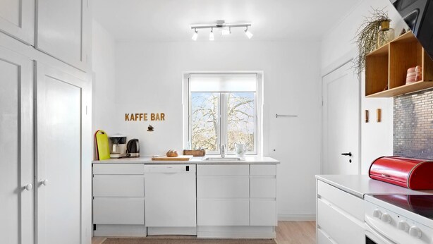A modern kitchen with white cabinetry, a built-in coffee station, a window with a view, and a red oven. - Gorgeous home in søby ærø with WiFi (Søby Ærø)