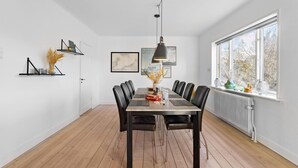 A dining room with a wooden table, black chairs, a pendant light, and a window with a view of trees. - Gorgeous home in søby ærø with WiFi (Søby Ærø)
