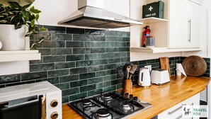 A modern kitchen with a gas stove, a range hood, a toaster, and a first aid kit on a shelf. - Alices Central Stay Parking  Motor Point Arena (Sneinton)