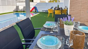 A poolside area with a table set for dining, a slide, and outdoor seating. - Villa Allegra: Private Pool & Modern Comfort (Protaras)