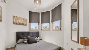 A bedroom with a bed, a bedside table, a lamp, and a window with a view. - Villa Allegra: Private Pool & Modern Comfort (Protaras)