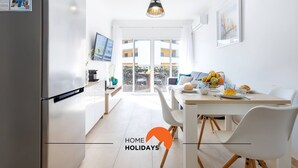 Cocina moderna con comedor, refrigerador, televisor y vistas al exterior.