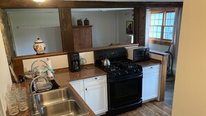 Cocina compacta con pileta, estufa, microondas y alacenas blancas.