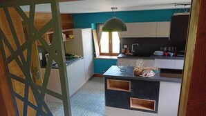 A compact kitchen with a window, a pendant light, and a built-in island with storage. - LE Chalet Favre - Hauteluce (HAUTELUCE)