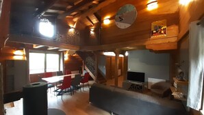 A spacious room with a wooden ceiling, a large clock, a television, and a seating area with a sofa and chairs. - LE Chalet Favre - Hauteluce (HAUTELUCE)
