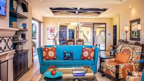 Un salon spacieux avec un canapé bleu, des fauteuils à motifs et une table basse.