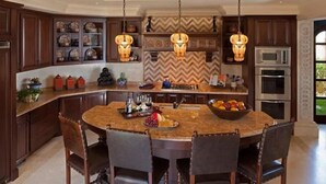 Une cuisine spacieuse dotée d’un grand îlot central, de meubles de cuisine en bois foncé et d’une cuisinière moderne.