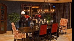 Un coin repas avec une table en bois, des chaises à revêtement rouge et un lustre.