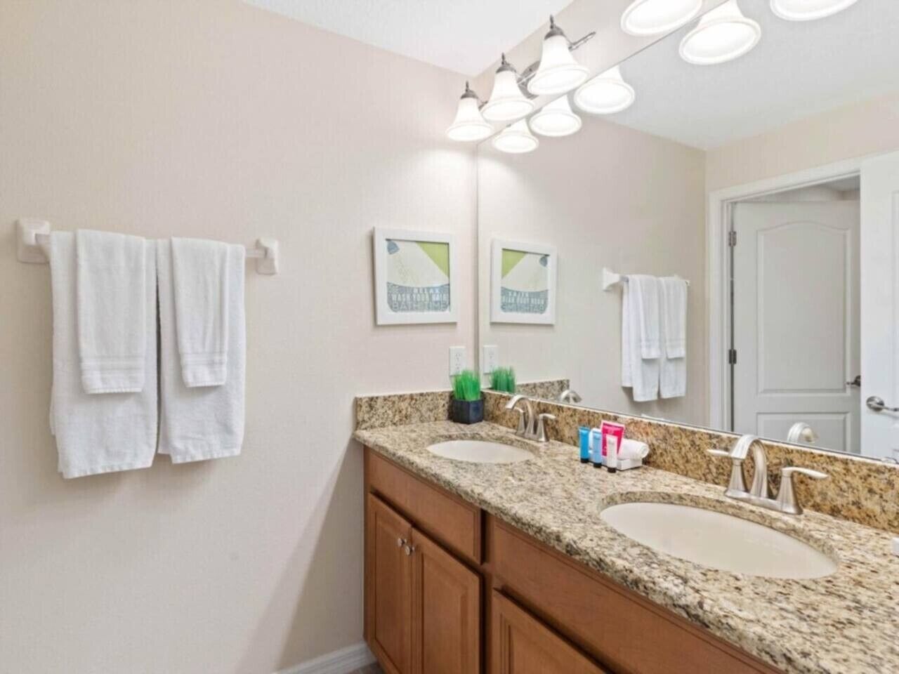 A bathroom with two sinks, a mirror, and towels on hooks.