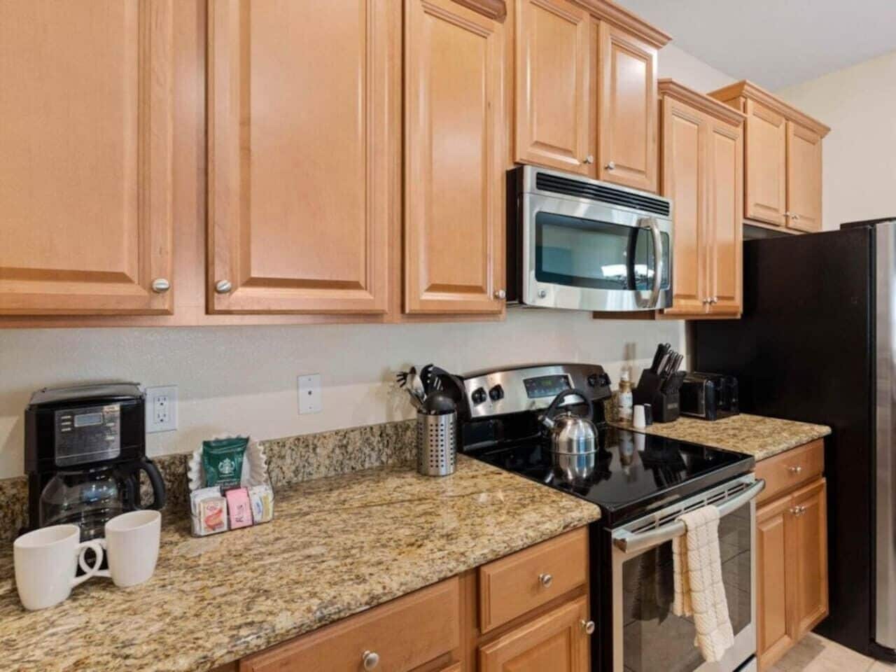 A kitchen with wooden cabinets, a stainless steel microwave, a stove, and a refrigerator.