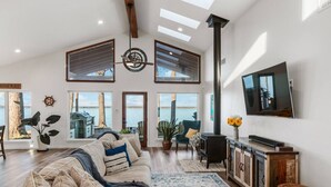 A spacious living room with a high ceiling, large windows, a fireplace, and a television mounted on the wall. - Perfect Lakehouse ~Dock w/ 2 slips ~Kayaks ~Ramp (Pittsburg)