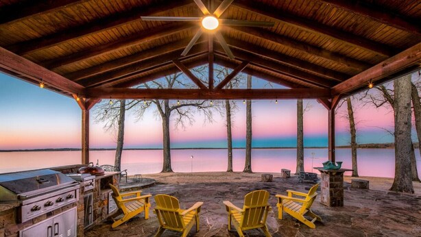 A covered outdoor area with a grill, chairs, and a view of a lake at sunset. - Perfect Lakehouse ~Dock w/ 2 slips ~Kayaks ~Ramp (Pittsburg)