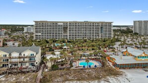 Ein großes Hotel mit mehreren Stockwerken, einem Schwimmbad und einem Strandbereich.