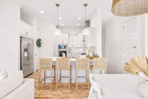 A modern kitchen with white cabinets, a stainless steel refrigerator, and a central island with bar stools.