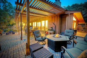 Un patio exterior con un pozo de fuego, mesas y sillas, y una pérgola.