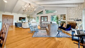 Un salón amplio con techo alto, piso de madera y un ventanal grande.
