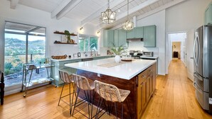 Cocina amplia con una isla grande, piso de madera y vista a un paisaje montañoso a través de un ventanal.
