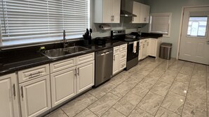 A modern kitchen with white cabinets, stainless steel appliances, and a tiled floor.
