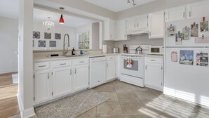 Una cocina moderna con armarios blancos, una campana extractora de acero inoxidable y un horno empotrado.