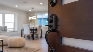 Un interior moderno con una puerta de madera, un comedor y una sala de estar con alfombra y reposapiés.