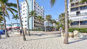 Ett hotell som ligger direkt vid stranden, med flera våningar, palmer och en sandstrand.